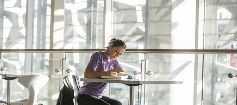 ACC student Halie sits reading at the Highland Campus.