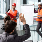 Men in helmets in front of white board