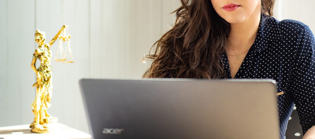 Person on laptop with Scales of Justice statue