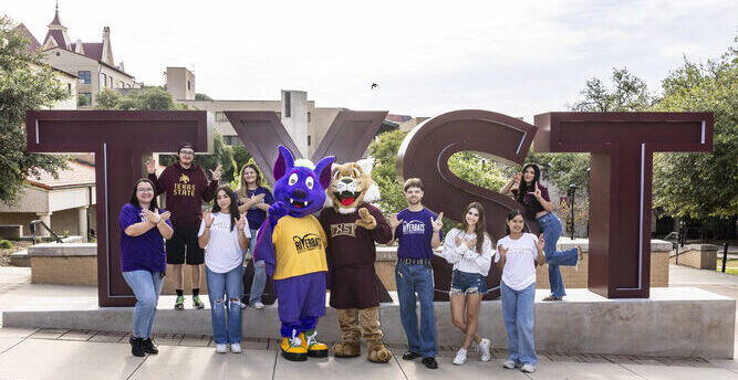 Students who transferred from Austin Community College (ACC) to Texas State University (TXST) pose together during a promotional photoshoot for the Bats to Cats transfer program on the TXST campus in San Marcos, Texas.